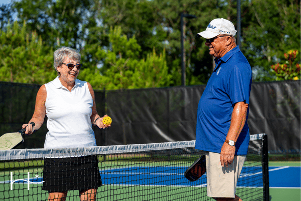 a couple playing pickleball in an active adult retirement living in texas